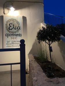 una señal en el lado de un edificio con un árbol en Elia Apartments en Agia Marina Aegina