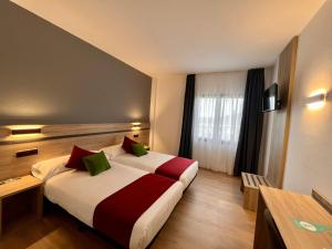Habitación de hotel con cama con almohadas rojas y verdes en Hotel Alda Malvasía, en Haro