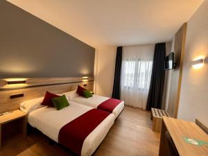 a hotel room with a bed with red and green pillows at Hotel Alda Malvasía in Haro