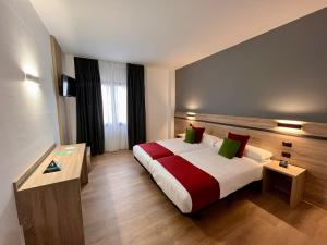 ein Hotelzimmer mit einem Bett mit roten und grünen Kissen in der Unterkunft Hotel Alda Malvasía in Haro