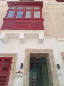 um edifício com janelas vermelhas e brancas e uma porta em Large & beautifully furnished 2 bedrooms ABON1-1 em Sliema