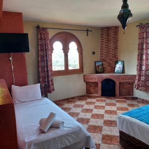 1 dormitorio con 2 camas y chimenea en Maison d´hôtes Amazir en Ouzoud