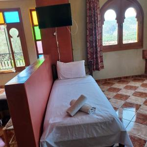 ein kleines Bett in einem Zimmer mit Fenstern in der Unterkunft Maison d´hôtes Amazir in Ouzoud