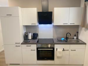 a kitchen with white cabinets and a sink at Moderne Ferienwohnung mit Balkon in Herxheim
