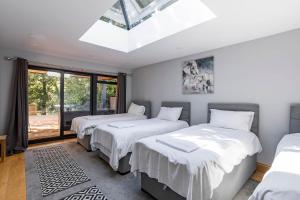 three beds in a room with a skylight at Kingsley Lake View & Paddocks - A group retreat with hot tub, sports bars & spectacular lake views in the Mendip Hills AONB in Chew Stoke