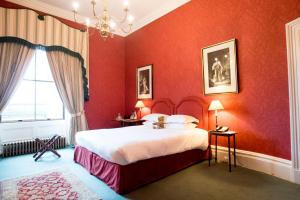 a bedroom with a large bed with red walls at The Victorian Wing in Shifnal