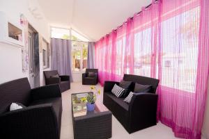 ein Wohnzimmer mit Stühlen und rosa Vorhängen in der Unterkunft Casinha VII by Innkeeper in Guia