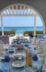 uma mesa longa com pratos de comida na praia em Belle maison en face de la mer em El Maamoura