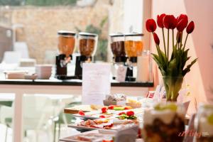 a table with plates of food and flowers and drinks at Spinola Stays in St. Julianʼs