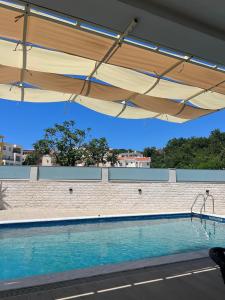 a large swimming pool with awning over it at Apartments Fat e Jet in Ulcinj