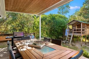 a patio with a wooden table and chairs at Gretel Cl 4 Nelson Bay in Nelson Bay