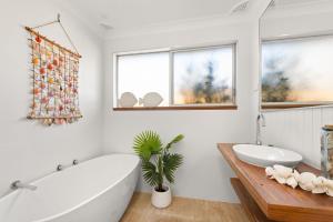 a bathroom with a tub and a sink and two windows at Gretel Cl 4 Nelson Bay in Nelson Bay