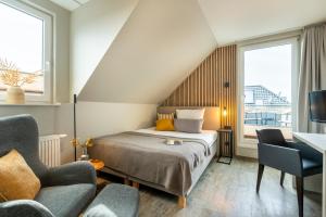 a bedroom with a bed and a desk and two chairs at Hotel Tide42 in Borkum