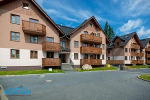 カルパチにあるApartamenty BlueSky - Nad Łomnicą 14 - centrum, blisko deptakaの木製バルコニー付きのアパートメントビル、駐車場