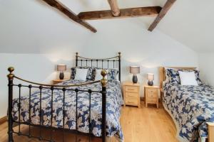 2 Betten in einem Schlafzimmer mit Holzböden und Holzbalken in der Unterkunft The Mill Nant Alyn in Rhydymwyn