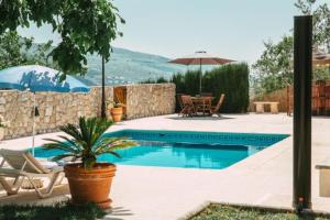 - une piscine avec une table, des chaises et un parasol dans l'établissement Casa Rural Alba Montis, à Güéjar-Sierra
