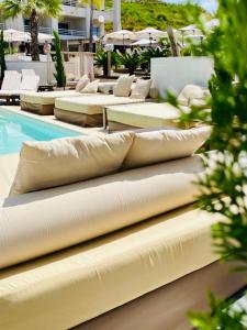 a row of pillows sitting next to a swimming pool at Bella Vista Hôtel, Suites & Maisons in Porticcio