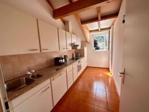 een keuken met witte kasten, een wastafel en een raam bij Cozy Ascona: attico mansardato in Ascona