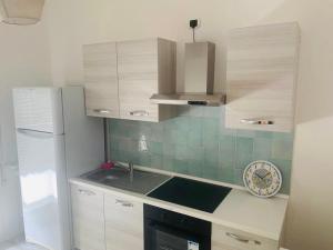 uma cozinha com armários brancos, um lavatório e um relógio em Appartamento Bilocale Moderno Marina Centro Rimini em Rimini