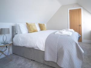 Cette chambre comprend un grand lit avec des draps blancs et une table. dans l'établissement Pass the Keys Chestnut Cottage parking stunning views, à Chipping Campden