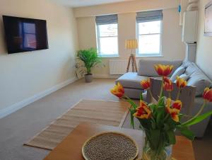 uma sala de estar com um sofá e uma mesa com flores em Barchester House Apartments Delux em Salisbury