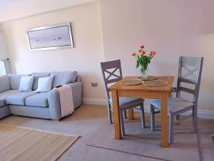 sala de estar con mesa, sillas y sofá en Barchester House Apartments Delux, en Salisbury