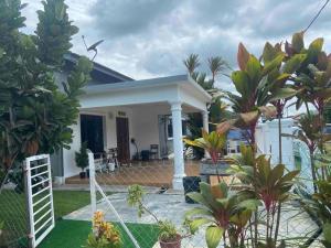 ein kleines weißes Haus mit Bäumen und Pflanzen in der Unterkunft Melaka Beach Villa in Malakka