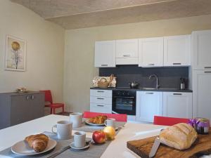 Modern Apartment in Agliana with Shared Garden في Agliana: مطبخ به دواليب بيضاء وطاولة عليها طعام