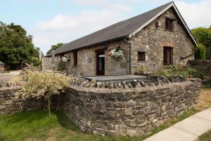 a stone house with a stone wall in front of it at Swallow Cottage in Bridgend