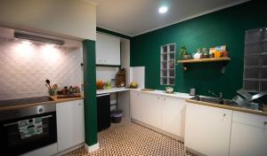 kuchnia z białymi szafkami i zieloną ścianą w obiekcie Boho Chic Apt w mieście Vila Franca de Xira