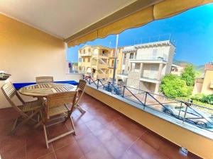 un balcone con tavolo, sedie e ampia finestra di Casagliana Apartments a Golfo Aranci