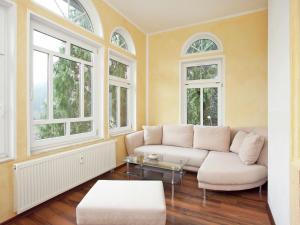 ein Wohnzimmer mit einem weißen Sofa und Fenstern in der Unterkunft Alluring Villa in Grunhainichen Borstendorf with Garden in Leubsdorf