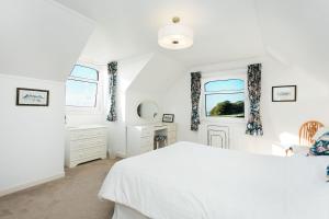 a white bedroom with a white bed and a window at High Auchenlarie Cottage in Gatehouse of Fleet