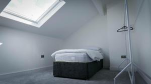 a bed in a white room with a window at Short City Stays in Hunslet