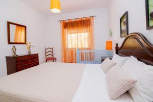 een slaapkamer met een groot wit bed en een wieg bij Casinha I by Innkeeper in Guia