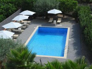 einen Blick über einen Pool mit Sonnenschirmen und Stühlen in der Unterkunft Apartment with air conditioning and salt pool in Santa Venerina
