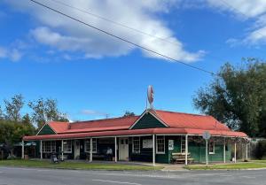a green building with a red roof on a street at Old Maffra Cottage in Maffra