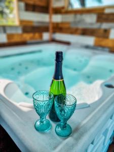 a bottle and two glasses next to a swimming pool at Le Cotil Ribes in Grangues