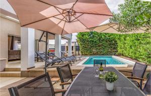 a table with an umbrella next to a swimming pool at Gorgeous Home In Sisan With Kitchen in Šišan