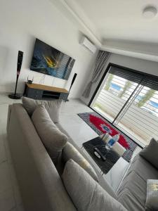 a living room with a couch and a large window at Étoile Harhoura in El Harhoura