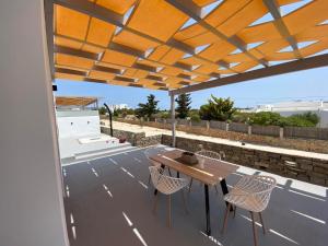 a patio with a wooden table and chairs under a roof at Bluebell Resort Villa SUNSET in Kampos Paros