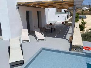 a patio with a pool and chairs and a table at Bluebell Resort Villa SUNSET in Kampos Paros