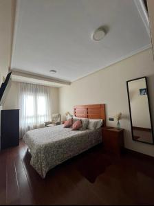 1 dormitorio con 1 cama grande y espejo en La Paz. Luminoso apartamento a la entrada de Llanes, en Llanes