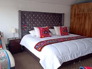 - une chambre avec un grand lit blanc et des oreillers rouges dans l'établissement uros waliski alpina house, à Puno