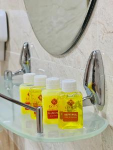 Trzy butelki żółtego płynu leżące na półce w łazience w obiekcie Komil Bukhara Boutique Hotel w mieście Buchara