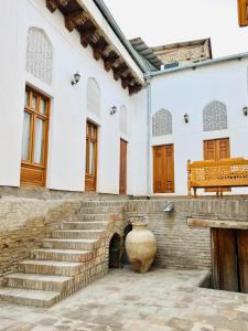 a building with stairs and a vase in a courtyard at Komil Bukhara Boutique Hotel in Bukhara