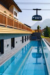 a swimming pool at a hotel with a ski lift above it at Hotel Petersboden in Lech am Arlberg