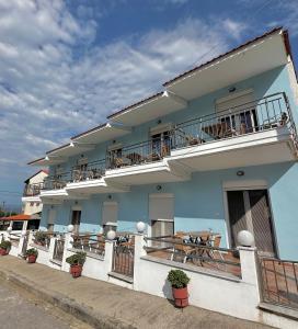 a blue building with tables and chairs on the balcony at Rooms Elena in Nea Potidaea