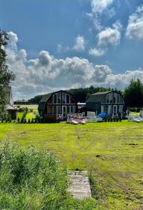 two barns in a field with a grass yard at Saulėlydis in Dreverna