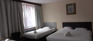 ブリュッセルにあるホテル アルベルゴのベッド2台と窓が備わるホテルルームです。